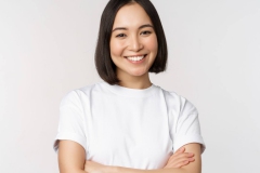 Portrait of happy asian woman smiling, posing confident, cross arms on chest, standing against studio background.